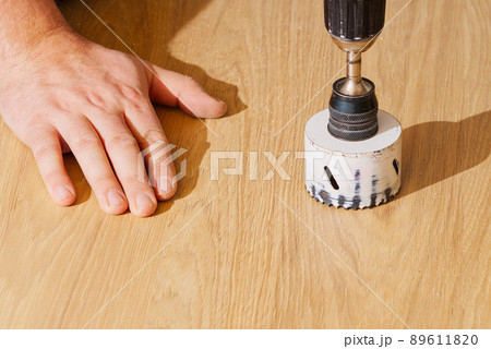 Worker with milling cutter in action at the workshop. Carpenter making holes in the wood board. DIY Worker with milling cutter in action at the workshop. Carpenter making holes in the wood board. DIY 89611820