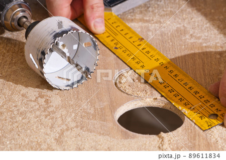 Worker with milling cutter in action at the workshop. Carpenter making holes in the wood board. DIY Worker with milling cutter in action at the workshop. Carpenter making holes in the wood board. DIY 89611834