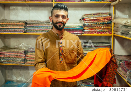 small shop owner indian man selling shawls at his store in arambol goa small shop owner indian man selling shawls at his store in arambol goa 89612734