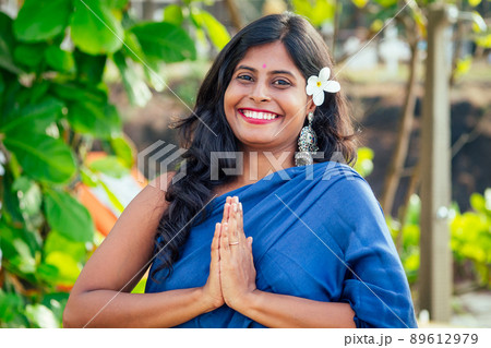 cheerful young indian woman with white flover in hair relaxing hand gesture namaste on beach in Goa cheerful young indian woman with white flover in hair relaxing hand gesture namaste on beach in Goa 89612979