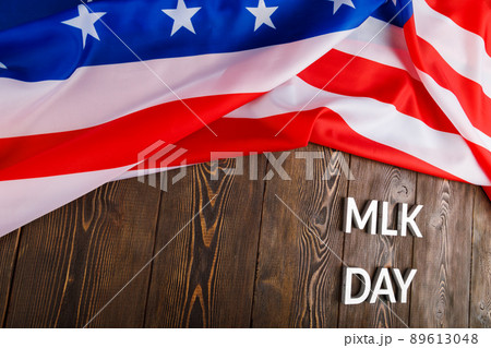 the word MLK day laid with silver metal letters on wooden surface with crumpled USA flag at upper side 89613048