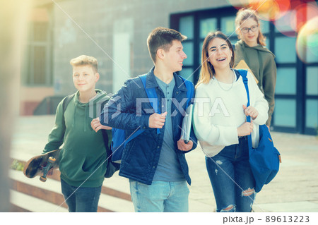 Smiling teenagers walking outside after lessons Smiling teenagers walking outside after lessons 89613223