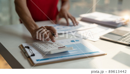 Close up of businessman or accountant hand holding pen working on calculator to calculate business data, accountancy document and laptop computer at office, business concept Close up of businessman or accountant hand holding pen working on calculator to calculate business data, accountancy document and laptop computer at office, business concept 89613442