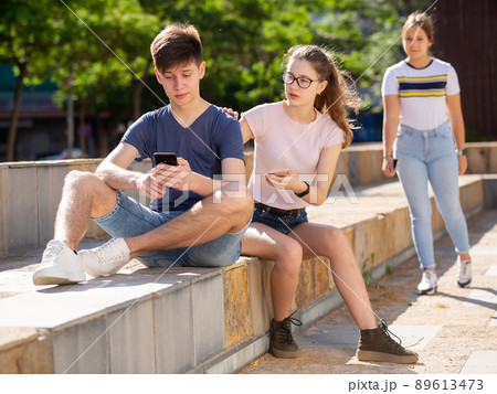 Company of teenagers with smartphones are communicating on walk 89613473