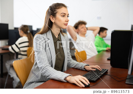 Focused woman sitting at table in computer room in public library 89613573