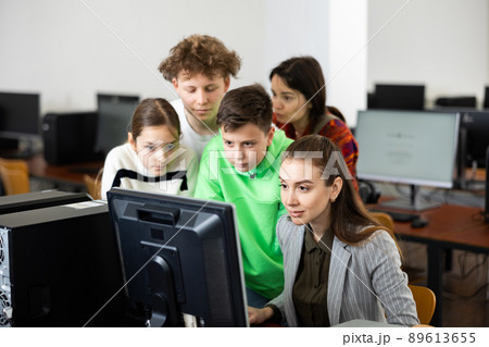 Female teacher and teen students looking at monitor screen during lesson 89613655