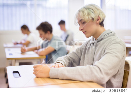 Teen boy sitting at desk in classroom 89613844