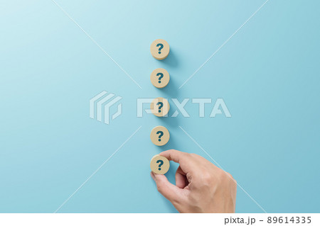 Hand holding wooden block shape with sign question mark symbol on blue background Hand holding wooden block shape with sign question mark symbol on blue background 89614335