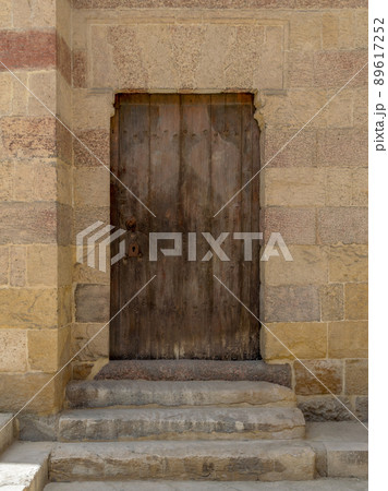 Grunge wooden aged door on exterior stone bricks wall Grunge wooden aged door on exterior stone bricks wall 89617252
