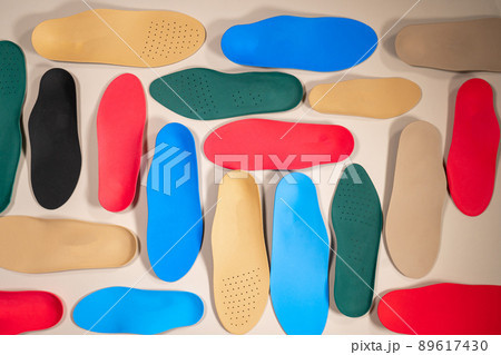 Orthopedic insoles are lined up on a wooden surface. samples of different orthopedic insoles. insoles with a variety of coating. 89617430