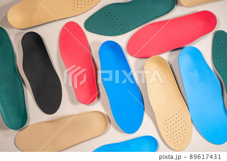 Orthopedic insoles are lined up on a wooden surface. samples of different orthopedic insoles. insoles with a variety of coating. 89617431