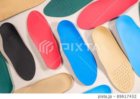 Orthopedic insoles are lined up on a wooden surface. samples of different orthopedic insoles. insoles with a variety of coating. 89617432