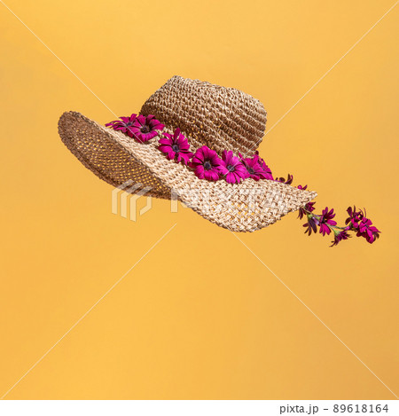 Minimal summer concept with flowers on a straw hat isolated on orange background. 89618164