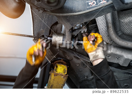 Closeup male tehnician mechanic greasy hands in gloves install new car oem suspensiom arm bushing during service at automotive workshop auto center. Vehicle safety checkup and maintenance concept Closeup male tehnician mechanic greasy hands in gloves install new car oem suspensiom arm bushing during service at automotive workshop auto center. Vehicle safety checkup and maintenance concept 89622535