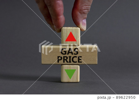 Gas price symbol. Businessman holds a wooden cube with arrow symbolizing that Gas price are going down or up. Beautiful grey table grey background. Business and gas price concept. Copy space. 89622950