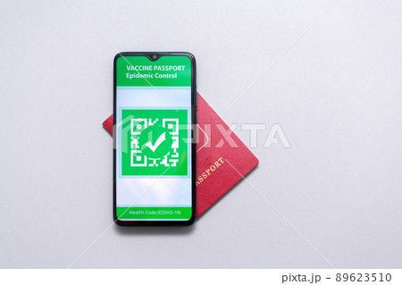 Electronic Immunity passport with a COVID-19 vaccination stamp on a smartphone screen with passport on the world map. Flat lay. Medicine and health concept. Copy space Electronic Immunity passport with a COVID-19 vaccination stamp on a smartphone screen with passport on the world map. Flat lay. Medicine and health concept. Copy space 89623510