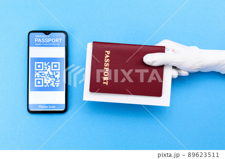 A hand in glove holds a passport. Cellphone screen with an electronic health passport with qr-code. Flat lay. Concept of Covid-19 test for travel 89623511