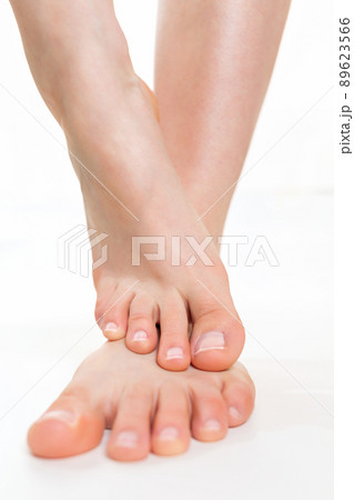 Female beautiful feet lying one on top of the other, close-up on an isolated white background. Concept of cosmetology, dermatology and pedicure 89623566