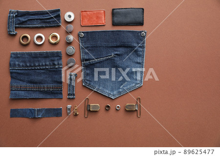 Flat lay composition with garment accessories and cutting details for jeans on brown background 89625477