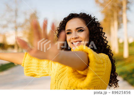 close-up. Girl with a beautiful smile and dark curly hair pulls her hands to the screen 89625856