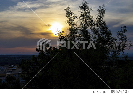 Sunset. Sunset with high clouds leaving the sky orange and blue. Backlight of the leaves and branches of the trees in a park in Madrid, in Spain. Europe. Horizontal photography. Sunset. Sunset with high clouds leaving the sky orange and blue. Backlight of the leaves and branches of the trees in a park in Madrid, in Spain. Europe. Horizontal photography. 89626585