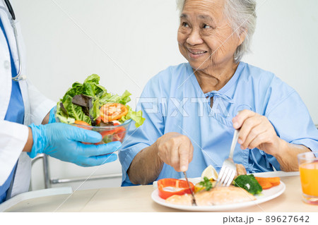 Asian senior or elderly old lady woman patient eating breakfast vegetable healthy food with hope and happy while sitting and hungry on bed in hospital. 89627642