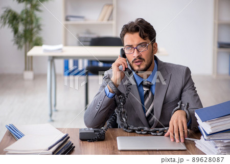 Young chained male employee sitting in the office Young chained male employee sitting in the office 89628087