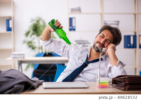 Young alcohol addicted employee sitting in the office 89628532