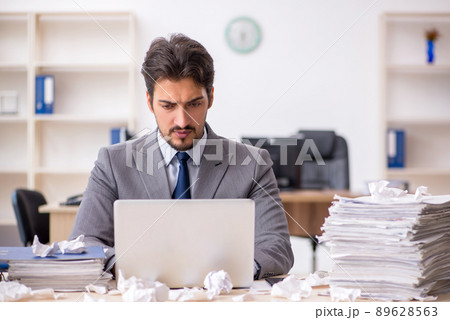 Young male employee and too much work in the office 89628563
