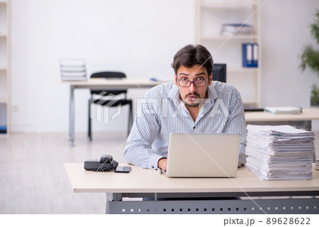 Young male employee and too much work in the office 89628622