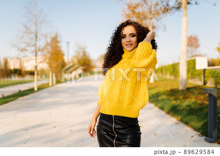 On the park track stands a slender searing brunette with curly long hair and smiles straightening their hand 89629584