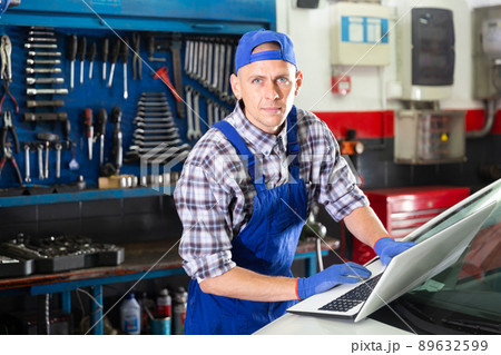 Mechanic man using laptop checking car in workshop Mechanic man using laptop checking car in workshop 89632599