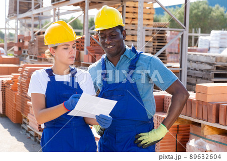 Two storekeepers with an estimate in their hands discuss working issues in the warehouse 89632604
