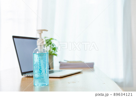 Bottle of liquid hand sanitizer on the wooden table in office, prevention from COVID19 or coronavirus pandemic concept. Using an alcohol gel and alway clean up a workplace can protect from COVID-19. Bottle of liquid hand sanitizer on the wooden table in office, prevention from COVID19 or coronavirus pandemic concept. Using an alcohol gel and alway clean up a workplace can protect from COVID-19. 89634121