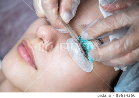 The master combs the eyelashes of a woman with a fish applicator.  89634266