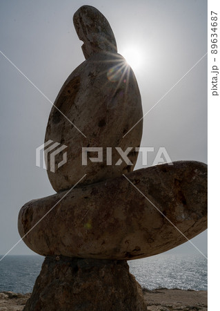 Sculpture symbol made of large pebbles against the blue sky 89634687