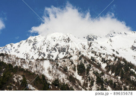 青空の中、天候が変わりそうな雲がかかる山頂 89635678