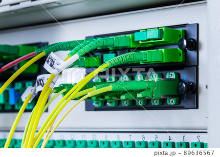 fiber optic cables plugged in network switch panel inside data center 89636567