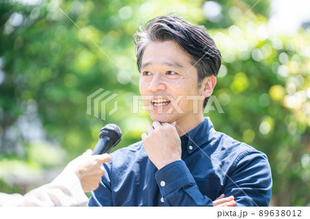 インタビューを受けるミドル男性（取材・マイク） 89638012