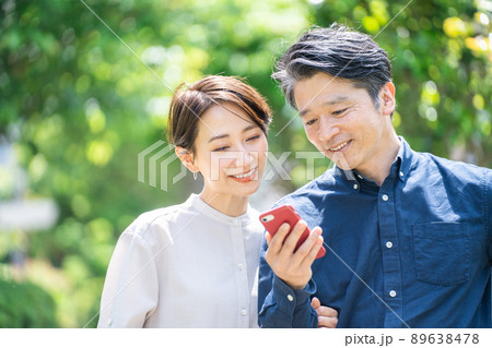 スマホを見るミドル夫婦(カップル・屋外・新緑・笑顔) スマホを見るミドル夫婦(カップル・屋外・新緑・笑顔) 89638478