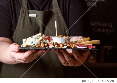 Waitress holding black stone board with delicacies. Waitress holding black stone board with delicacies. 89639720