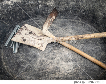 The old plastic bucket with the hoe and shovel for mixing the cement mortar. 89639896