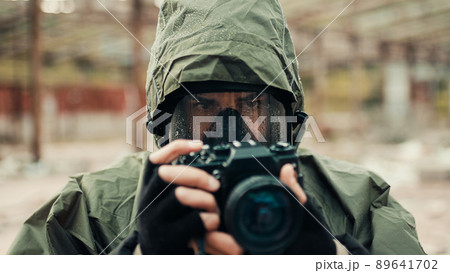 Military man with gas mask and camera photographs the destruction of the bomb Military man with gas mask and camera photographs the destruction of the bomb 89641702