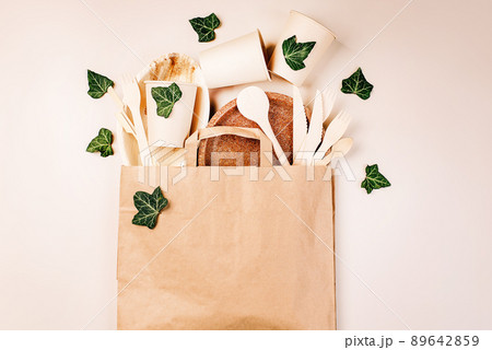 Recycling,eco-friendly concept.Disposable eco cutlery,plates,spoons,knives,forks on a light background.Craft paper bag for food delivery.Copy space.Eco craft paper tableware,cups,fast food containers. 89642859