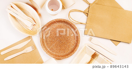 Eco craft paper tableware,cups,fast food containers.Recycling,eco-friendly concept.Disposable eco cutlery,plates,spoons,knives,forks on a light background.Craft paper bag for food delivery.Copy space. 89643143