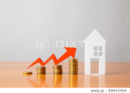 Coins on a table, a red up arrow and house. The concept of the rising price of real estate Coins on a table, a red up arrow and house. The concept of the rising price of real estate 89643404