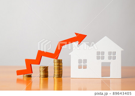 Coins on a table, a red up arrow and house. The concept of the rising price of real estate 89643405