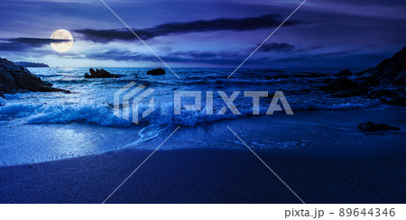 empty beach at night. beautiful landscape at the sea. waves washing the sand and stones on the shore. clouds glowing in full moon light. calm summer vacation and travel destination concept empty beach at night. beautiful landscape at the sea. waves washing the sand and stones on the shore. clouds glowing in full moon light. calm summer vacation and travel destination concept 89644346