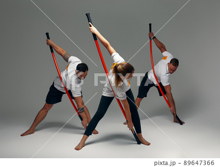 Two men and woman aikido fighters with wooden fight stick posing in studio, fight demonstration 89647366