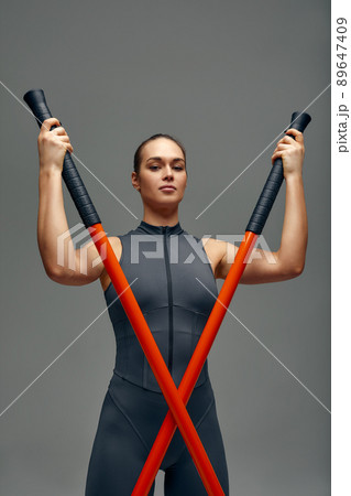 beautiful girl in sports uniform is training kung fu in the studio, fighter athlete, practicing martial arts with a stick 89647409